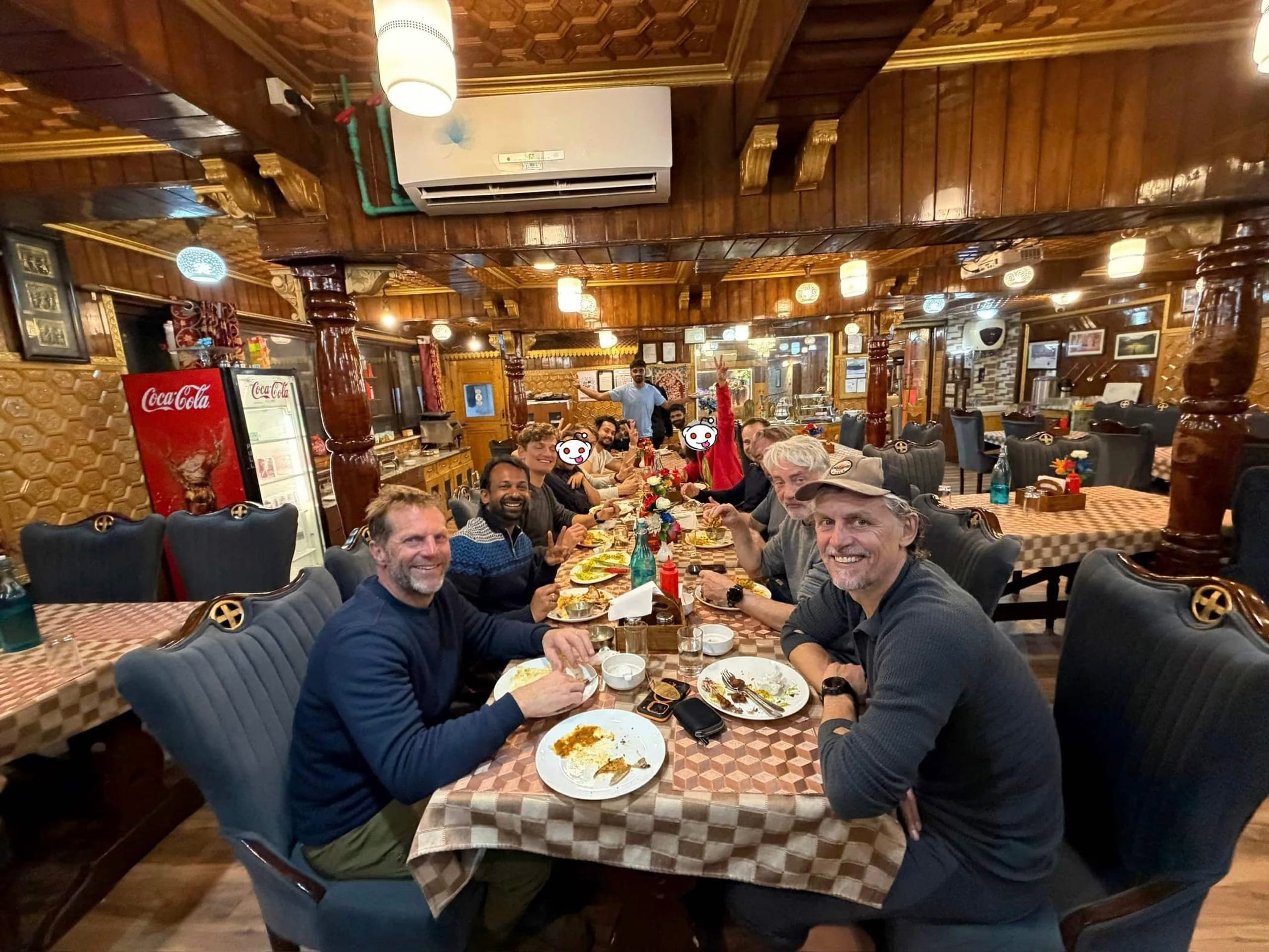 A group eating together at a long table in a wood panelled Gulmarg restaurant.