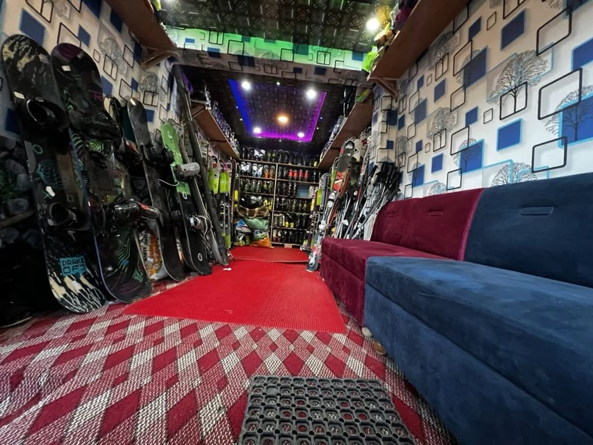 Inside the Gulmarg Snowkings ski shop, with snowboards and skis racked along the walls and bench seating down the middle.